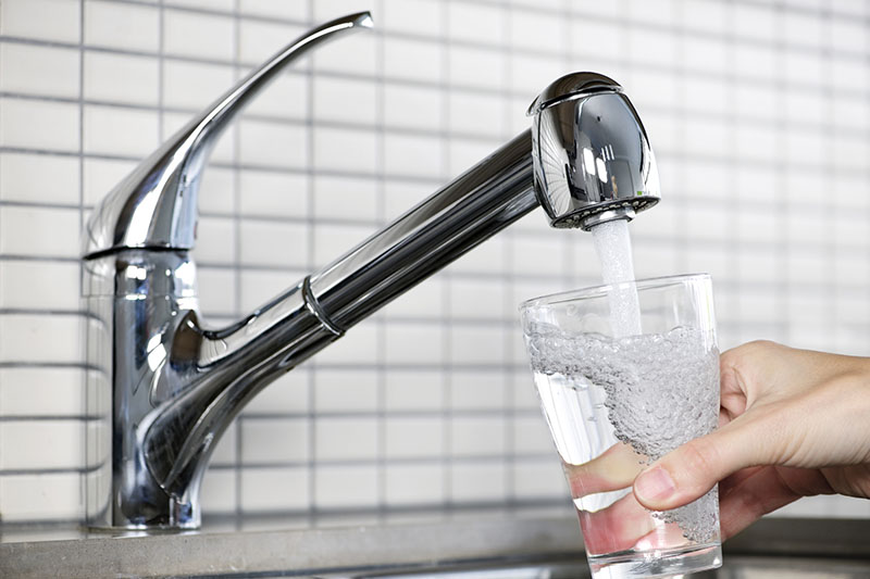 Filling glass of tap water before testing while performing home inspection services 